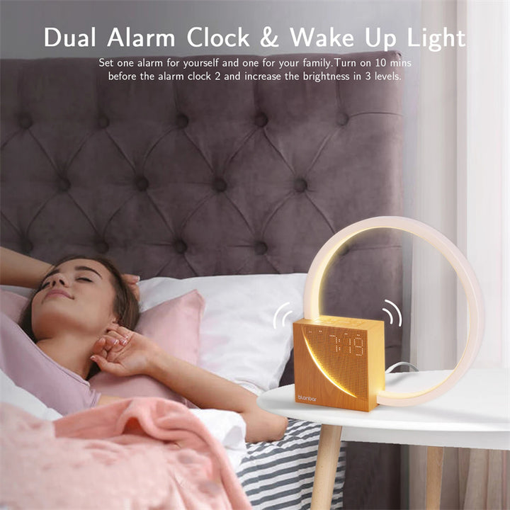 Woman in bed with a dual alarm clock and wake-up light on a nightstand.